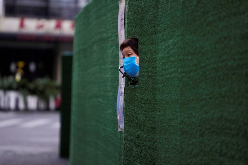A resident looks out through a gap in the barrier at a residential area during a COVID-19 lockdown in Shanghai, China, May 6, 2022. Credit: Reuters
