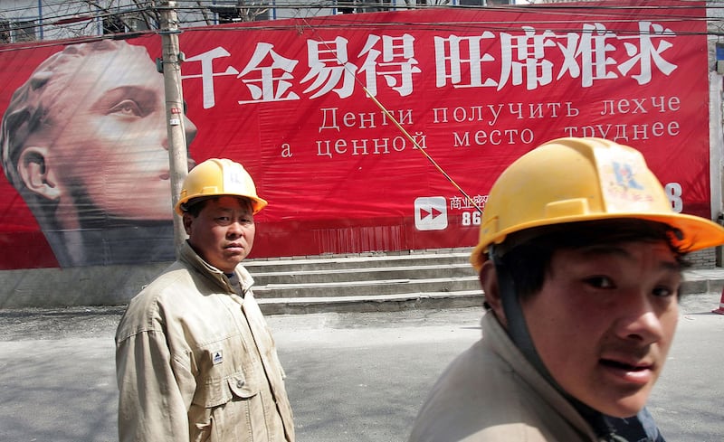 资料图片:2006年3月19日,建筑工人在北京俄罗斯城雅宝路的中文和俄文广告牌走过。(法新社)