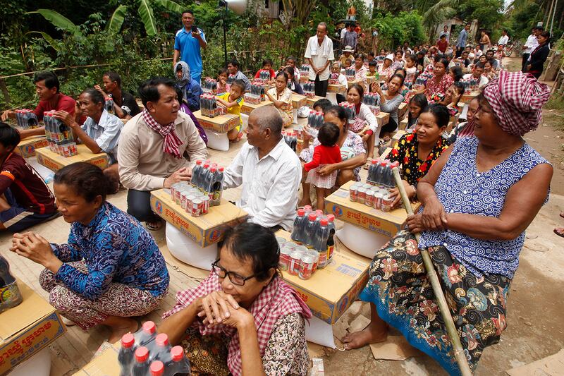Phos Sovann, center left, the director general of Cambodia’s Ministry of Information, talks with villagers as they wait for gifts from the Cambodian Red Cross near the Mekong River northeast of Phnom Penh, Aug. 18, 2018.