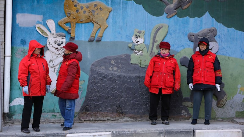 戴着红袖章的老年志愿者,在北京市中心的街道路旁值班。(路透社)