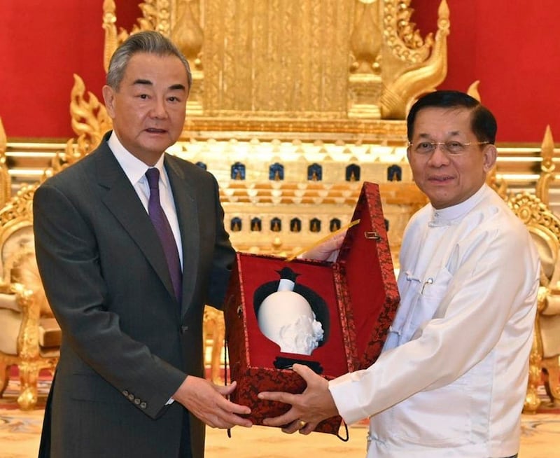 Myanmar junta leader Senior Gen. Min Aung Hlaing, right, and China's Foreign Minister Wang Yi hold a gift during their meeting Aug. 14, 2024, in Naypyidaw. (Myanmar Military Information Team via AP)