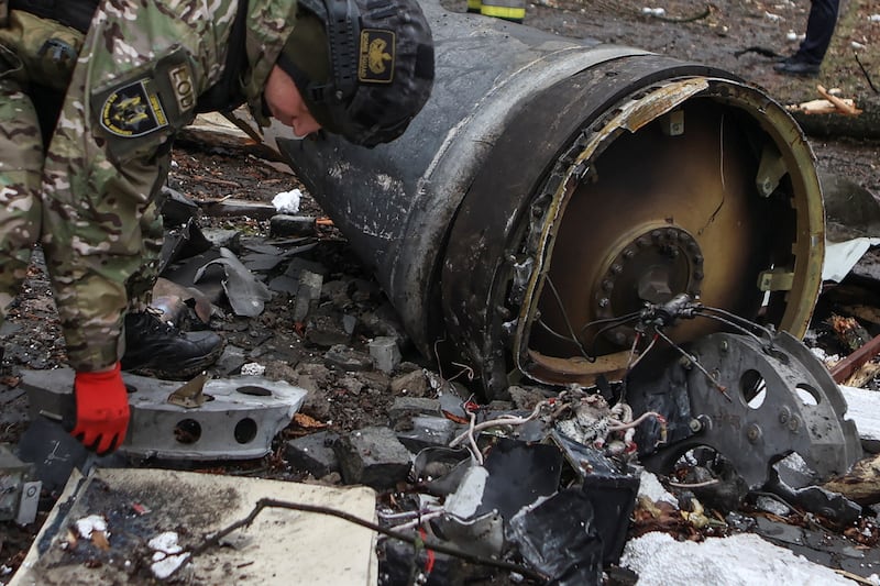 A Ukrainian bomb squad member examines the remains of an unidentified missile that struck residential buildings during a Russian attack, in Kharkiv, Ukraine, on Jan. 2, 2024.