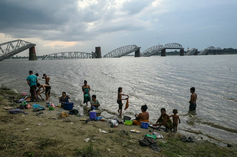 People take bath in the Irrawaddy River in front of the collapsed Ava Bridge, also known as the Inwa Bridge, in Mandalay on April 13, 2025, days after an earthquake struck central Myanmar.