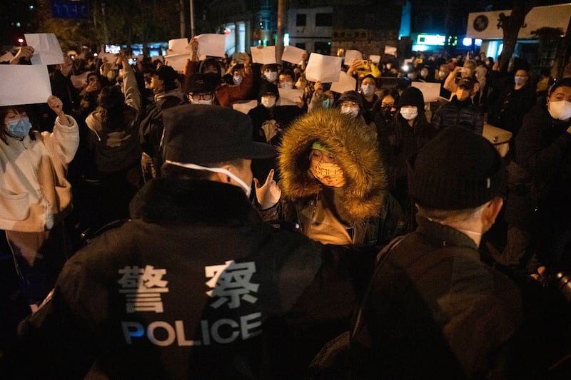 2022年11月27日，中国警察在北京与举着白纸的抗议者对峙。（美联社）