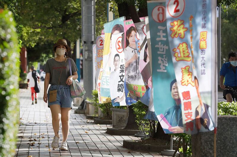 2022年11月20日,台湾台北,人们走过候选人的竞选旗帜。(美联社)