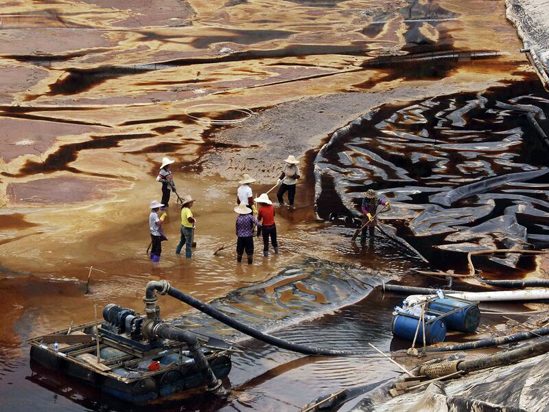 Workers drain away polluted water near the Zijin copper mine in Shanghang, China, July 13, 2010.