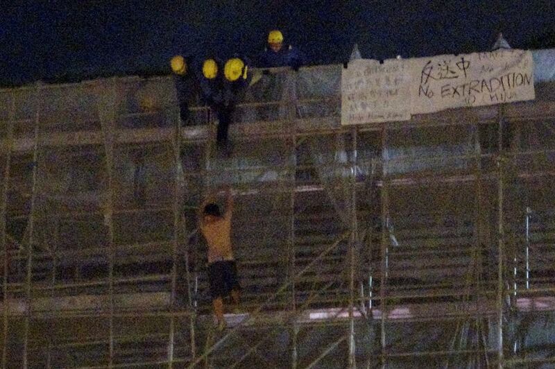 2019年6月15日,一名抗议者在太古广场平台悬挂标语时,从大楼周围的施工脚手架上掉下来,消防队员正试图营救他。(路透社)