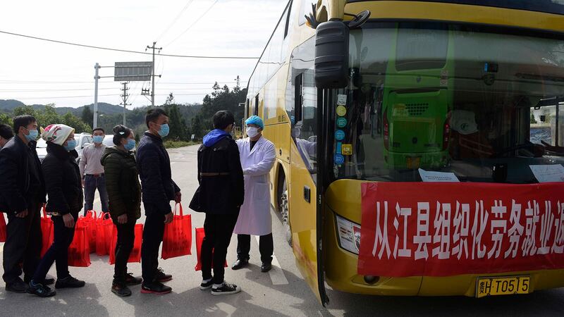 在面临经济下行的压力下,中央推动全国复工但工厂运作困难重重。图为,2020年2月18日,贵州省江县返回广西工作乘坐包车前,对工人测量体温。(法新社)