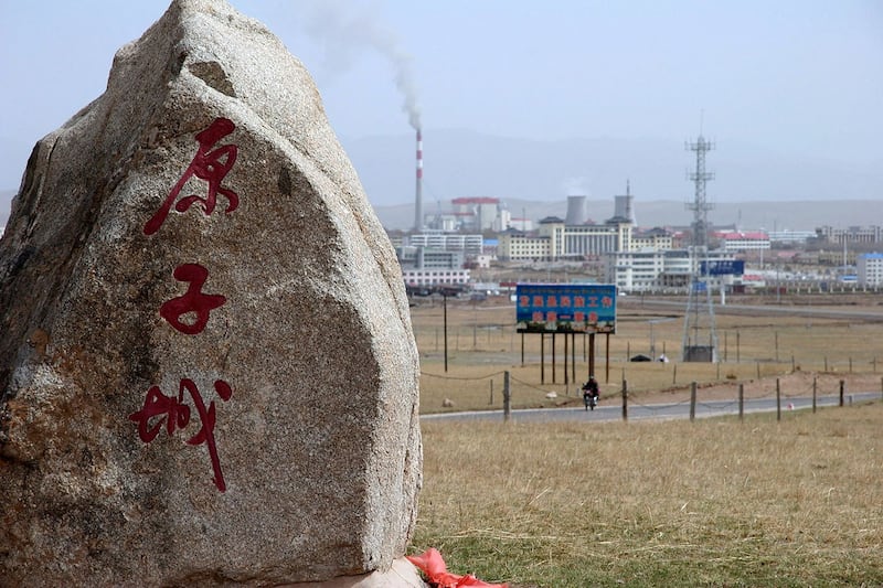 2007 年 5 月 12 日,中国青海省海盐市,在通往中国第一个核武器基地的道路上,一块纪念碑石标志着“核城”,背景是一座新的工业城市,该基地已解密并向游客开放。(法新社)