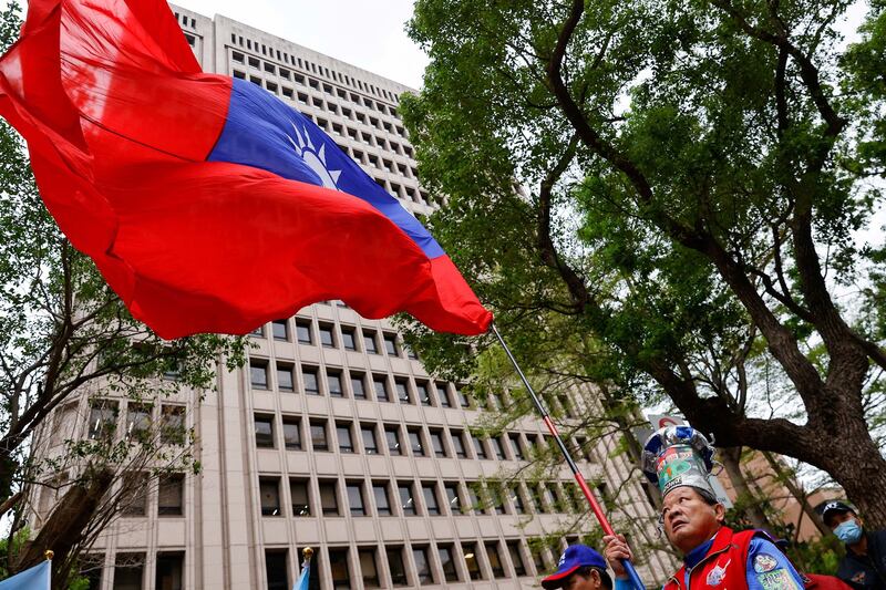 A supporter of the main opposition party Kuomintang (KMT) waves a Taiwanese flag outside of the Central Election Commission in Taipei in 2023. (Ann Wang/Reuters)