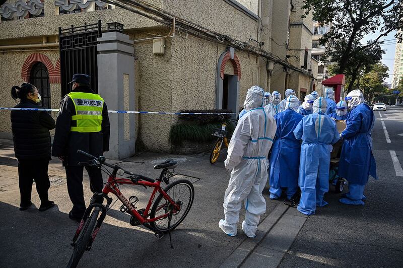 2022 年 3 月 23 日,穿着防护装备的卫生工作者在上海一住宅区。(法新社 )