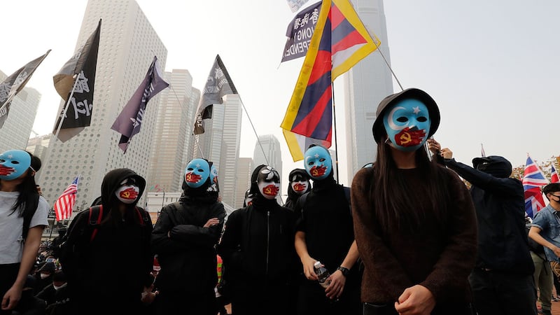 2019年12月22日,在香港中心地带举行主题为"声援维吾尔人权"的集会,身着黑衣的蒙面示威者高举写有"自由香港"字样的横幅。 (美联社)