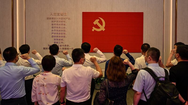 资料图片:2021 年 6 月 22 日,上海当地政府组织的一次媒体巡展期间,人们在中国共产党第一次全国代表大会博物馆党旗前宣誓。(法新社)