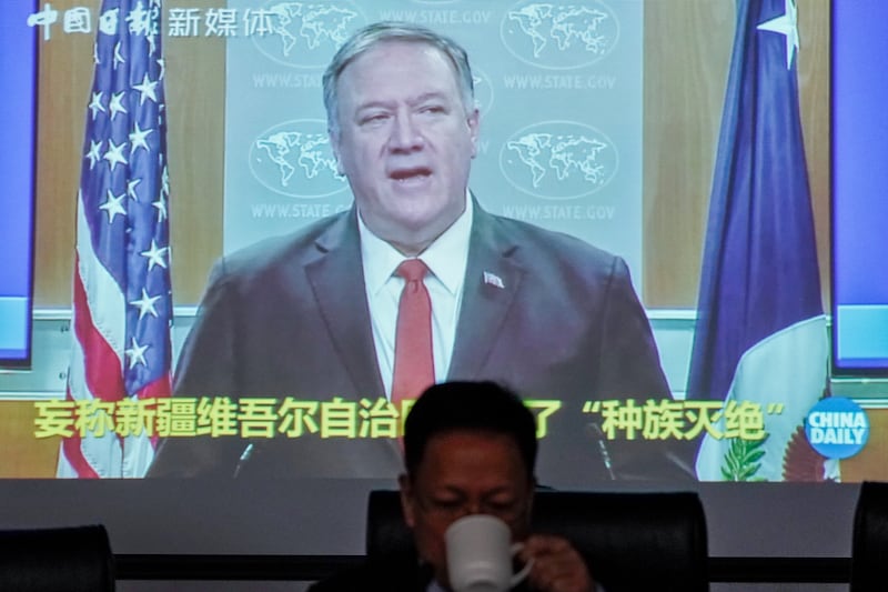 Xu Guixiang, a spokesperson for Xinjiang's Communist Party, drinks as a screen showing a footage of former U.S. Secretary of State Mike Pompeo, at the Ministry of Foreign Affairs office in Beijing, Monday, Feb. 1, 2021. Xu accused Pompeo of trying to undermine Beijing's relations with President Joe Biden by declaring China's actions against the Uyghur ethnic group a "genocide."